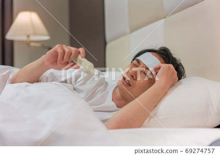 一個年輕人在晚上用溫度計測量他的熱量 一個年輕人在晚上用溫度計測量他的熱量 69274757