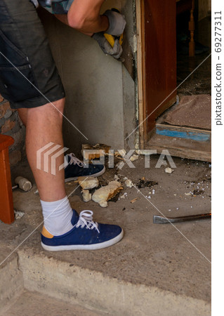Dismantling of old entrance doors, old wooden box and door, the master cuts, cuts a wooden box from the wall with a hand saw. Dismantling of old entrance doors, old wooden box and door, the master cuts, cuts a wooden box from the wall with a hand saw. 69277311