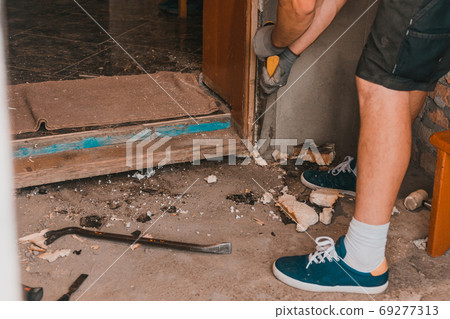 Dismantling of old entrance doors, old wooden box and door, the master cuts, cuts a wooden box from the wall with a hand saw. Dismantling of old entrance doors, old wooden box and door, the master cuts, cuts a wooden box from the wall with a hand saw. 69277313