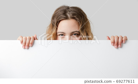 16 year old teenager looks at the camera over a white partition 16 year old teenager looks at the camera over a white partition 69277611