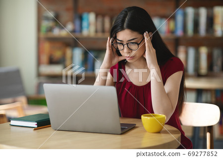 Concentrated Asian Nerd Student Girl In Eyeglasses Studying Online With Laptop In Cafe 69277852