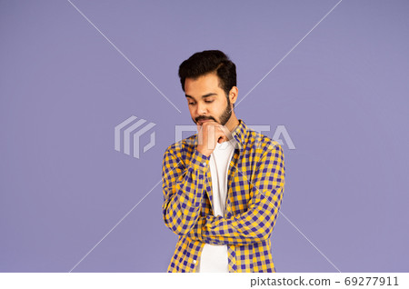 Thoughtful Indian guy pondering over something on lilac background 69277911