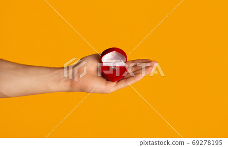 Unrecognizable man holding box with engagement ring on orange background, closeup Unrecognizable man holding box with engagement ring on orange background, closeup 69278195
