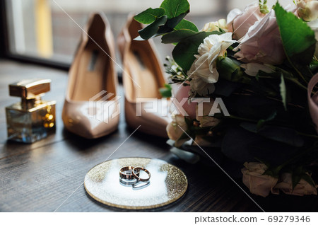 Luxurious wedding bouquet next to the rings of the bride and groom. The bride's shoes with heels 69279346