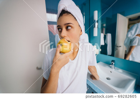 Young caucasian woman in bathroom, hold apple. 69282605