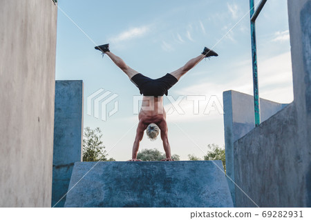 Handstand yoga pose by athlete man on the sport ground outdoors, natural lifestyle photo. 69282931