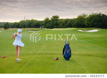 Woman in White Uniform Hit Golf Ball . Woman in White Uniform Hit Golf Ball . 69283573