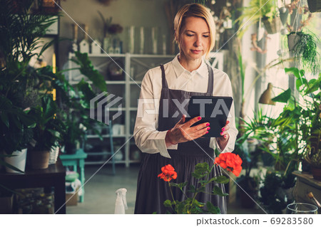 Serious Florist Woman Concentrated On Work From Tablet. Serious Florist Woman Concentrated On Work From Tablet. 69283580