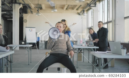 A young woman in an office throws a phone and rolls a colleague a man on a chair. All office employees join and dance together. Managers scatter money, paper and have fun. Front video. A young woman in an office throws a phone and rolls a colleague a man on a chair. All office employees join and dance together. Managers scatter money, paper and have fun. Front video. 69284103