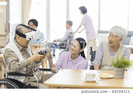 Senior man playing VR game and caregiver Nursing home Senior man playing VR game and caregiver Nursing home 69284221