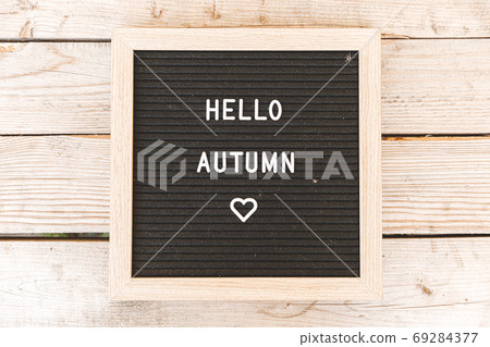 Autumnal Background. Black letter board with text phrase Hello Autumn lying on wooden palnks. Top view, flat lay. Thanksgiving banner. Hygge mood cold weather concept 69284377