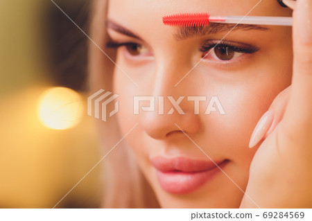 Young woman having professional eyebrow correction procedure in beauty salon. Young woman having professional eyebrow correction procedure in beauty salon. 69284569
