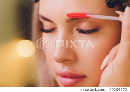 Young woman having professional eyebrow correction procedure in beauty salon. Young woman having professional eyebrow correction procedure in beauty salon. 69284570