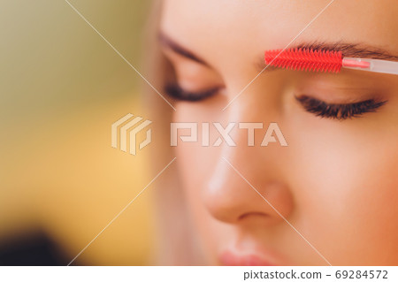 Young woman having professional eyebrow correction procedure in beauty salon. Young woman having professional eyebrow correction procedure in beauty salon. 69284572