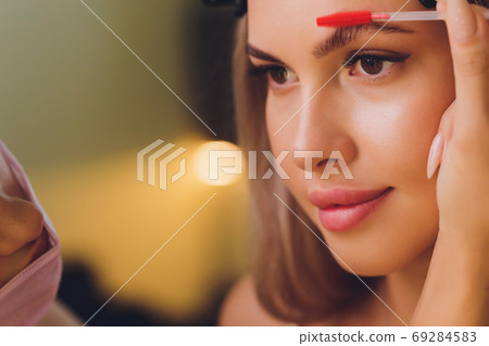 Young woman having professional eyebrow correction procedure in beauty salon. Young woman having professional eyebrow correction procedure in beauty salon. 69284583