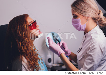 Close-up portrait of a female patient visiting dentist for teeth whitening in clinic,Teeth whitening procedure. Close-up portrait of a female patient visiting dentist for teeth whitening in clinic,Teeth whitening procedure. 69284764