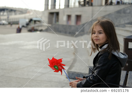 Little girl in urban surroundings with red wind spinner 69285176