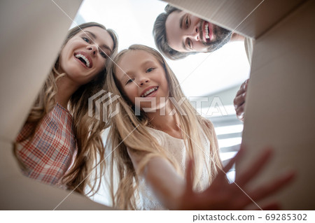 Happy family opening a cardboard and looking excited Happy family opening a cardboard and looking excited 69285302