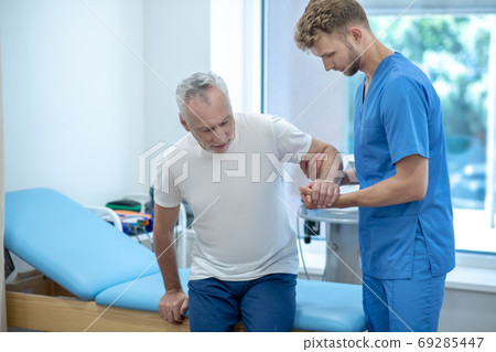 Elderly grayhaired man and helpful attentive doctor. Elderly grayhaired man and helpful attentive doctor. 69285447