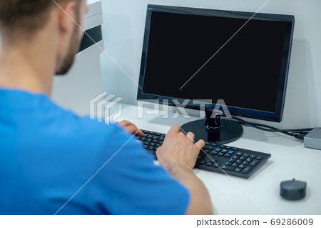 Male medic working at computer his back to camera 69286009