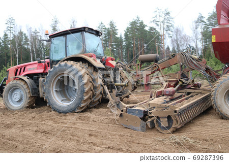 A powerful red tractor with a connected seeding 69287396