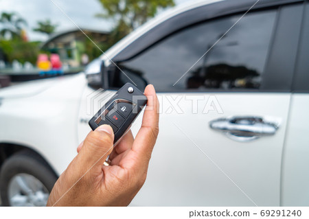 Hand pressing the button on the remote to lock or unlock the car Hand pressing the button on the remote to lock or unlock the car 69291240