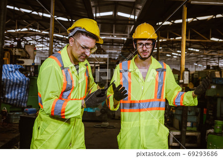 Engineer industry wearing safety uniform ,black gloves used radio communication for common and discussion work in factory industry Engineer industry wearing safety uniform ,black gloves used radio communication for common and discussion work in factory industry 69293686