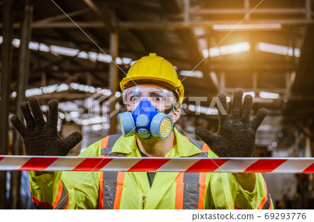 Engineer industry wearing safety uniform ,black gloves and gas mask show hand signal no entry chemical dangerous area in industry factory work. 69293776