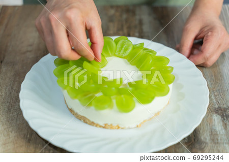 Woman's hands making Shine Muscat rare cheesecake/decoration Woman's hands making Shine Muscat rare cheesecake/decoration 69295244
