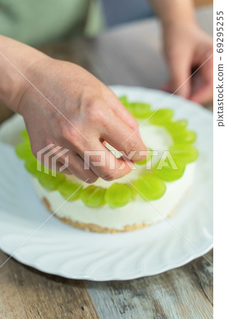 A woman's hands making a Shine Muscat rare cheesecake decoration 69295255