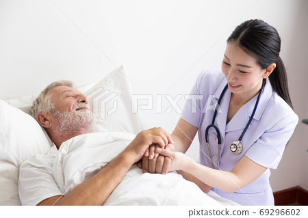 Nurse cares for elderly man lying in bed 69296602