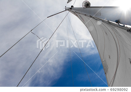 Bottom view of mast and sail of yacht on blue sky background, selective focus 69298092