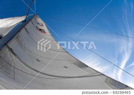 Bottom view of mast and sail of yacht on blue sky background, selective focus 69298465