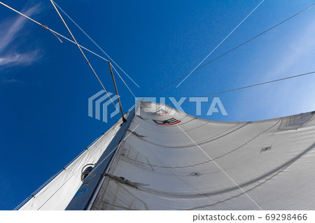 Bottom view of mast and sail of yacht on blue sky background, selective focus 69298466
