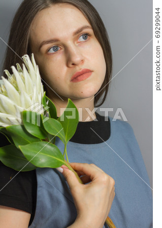 Portrait of brunette girl holds white huge protea, selective focus Portrait of brunette girl holds white huge protea, selective focus 69299044