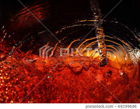 Alcoholic drink on a dark background, abstract splashing. Alcoholic drink on a dark background, abstract splashing. 69299686