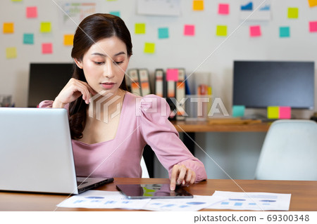 Business asian woman use tablet and labtop for search and note j 69300348