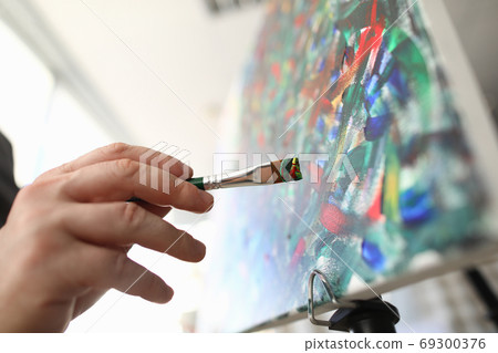 Brush for painting in hand and artist makes sketches. 69300376