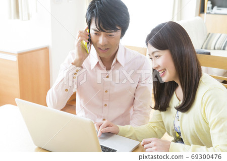 A couple calling while looking at a computer A couple calling while looking at a computer 69300476