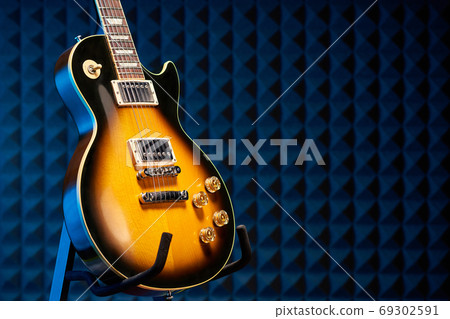 Sunburst electric guitar standing over acoustic foam panel background Sunburst electric guitar standing over acoustic foam panel background 69302591