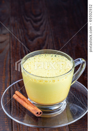 Moon milk with turmeric in glass cup, vertical Moon milk with turmeric in glass cup, vertical 69302932