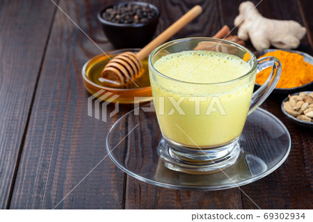 Moon milk with turmeric in glass cup, horizontal 69302934