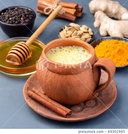 Yellow moon milk with turmeric in clay cup, square Yellow moon milk with turmeric in clay cup, square 69302985