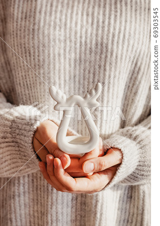 Feminine hands holding a deer shaped candlestick close-up. Feminine hands holding a deer shaped candlestick close-up. 69303545
