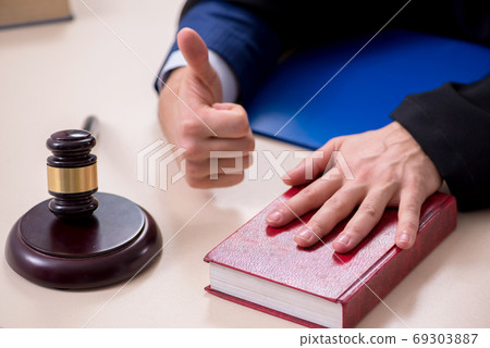 Young male judge working in courthouse 69303887