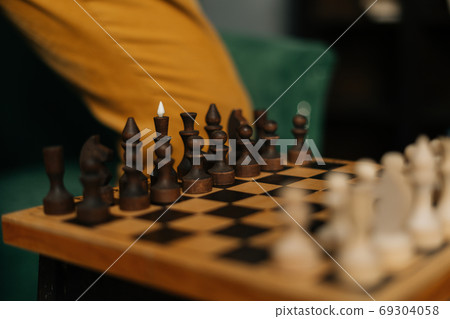 Side view of chessboard with placed chess pieces on black old vintage table, focus on background. 69304058