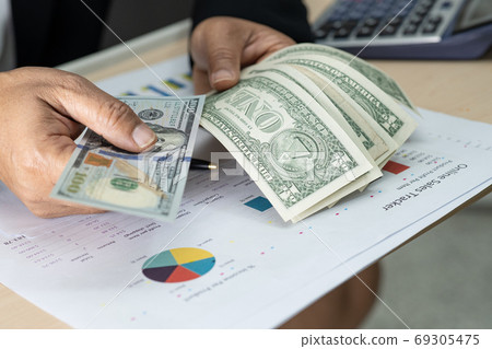 Asian accountant holding dollar banknotes, working, calculate and analyzing report project Asian accountant holding dollar banknotes, working, calculate and analyzing report project 69305475