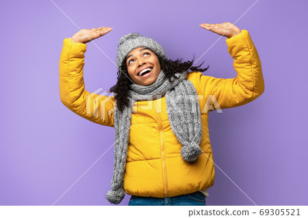 Cheerful Black Girl Holding Invisible Object Above Head, Purple Background Cheerful Black Girl Holding Invisible Object Above Head, Purple Background 69305521