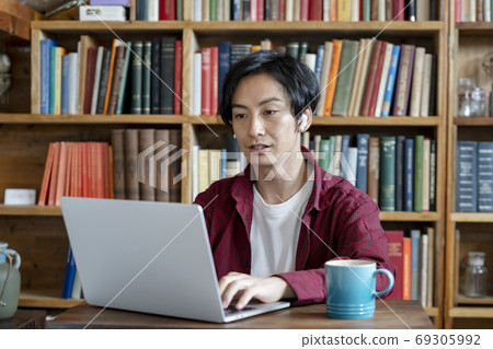 A young man working on a computer with wireless headphones 69305992