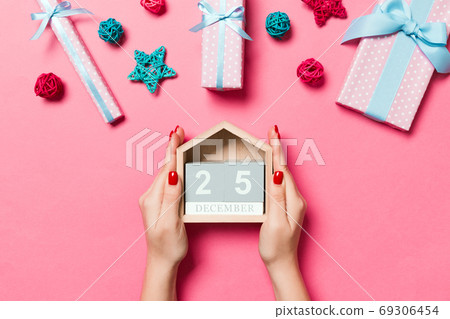 Top view of female hands holding calendar on pink background. Th Top view of female hands holding calendar on pink background. Th 69306454